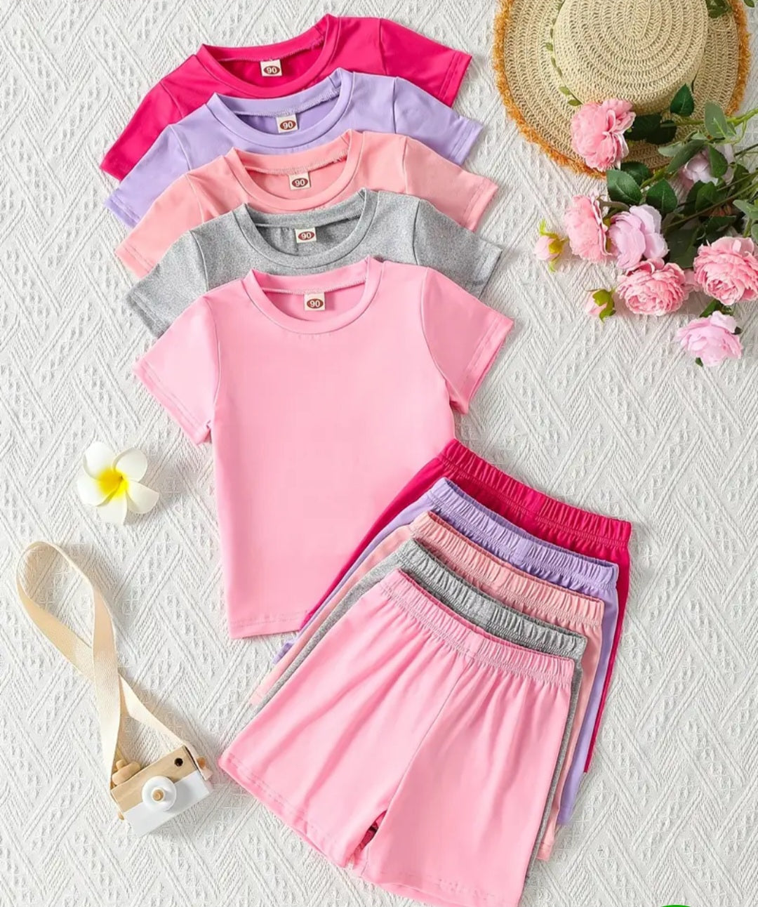 Girl's 5-Piece Summer Fashion Set featuring colorful knit solid color T-shirts and casual shorts, perfect for sunny days. Includes a variety of pink, purple, and gray hues, arranged with a cute camera and floral accents.