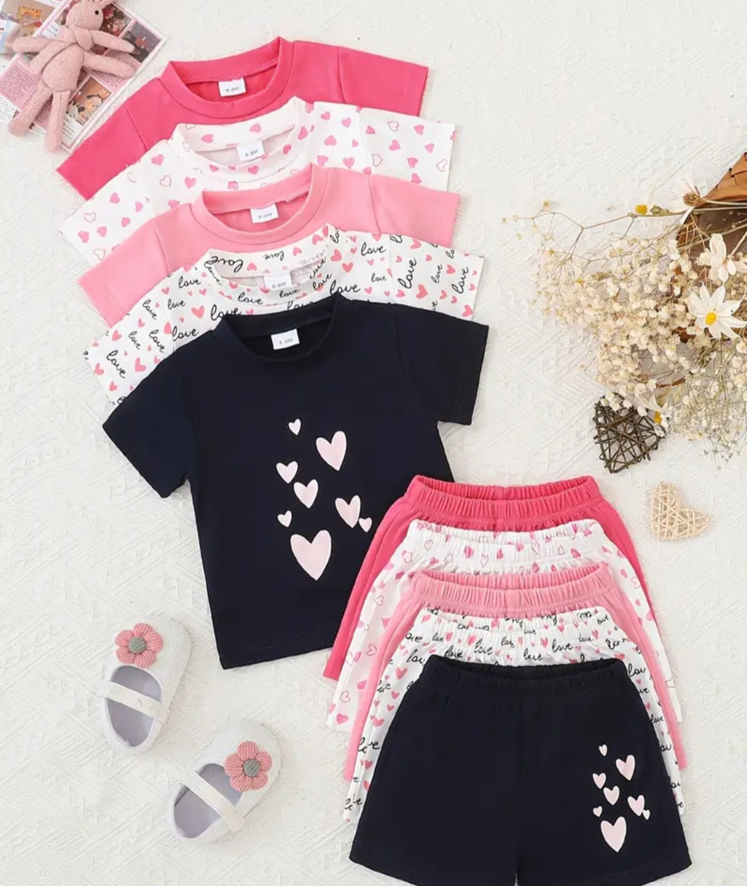 Charming outfits for girls and toddlers, featuring a variety of stylish and comfortable tops and shorts in vibrant colors and heart patterns, perfect for any occasion.